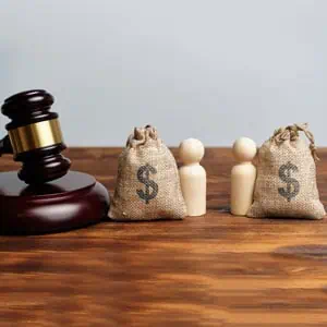 A judge's gavel rests beside money bags on a wooden table, symbolizing asset division in a divorce proceeding. - DC Nguyen Law